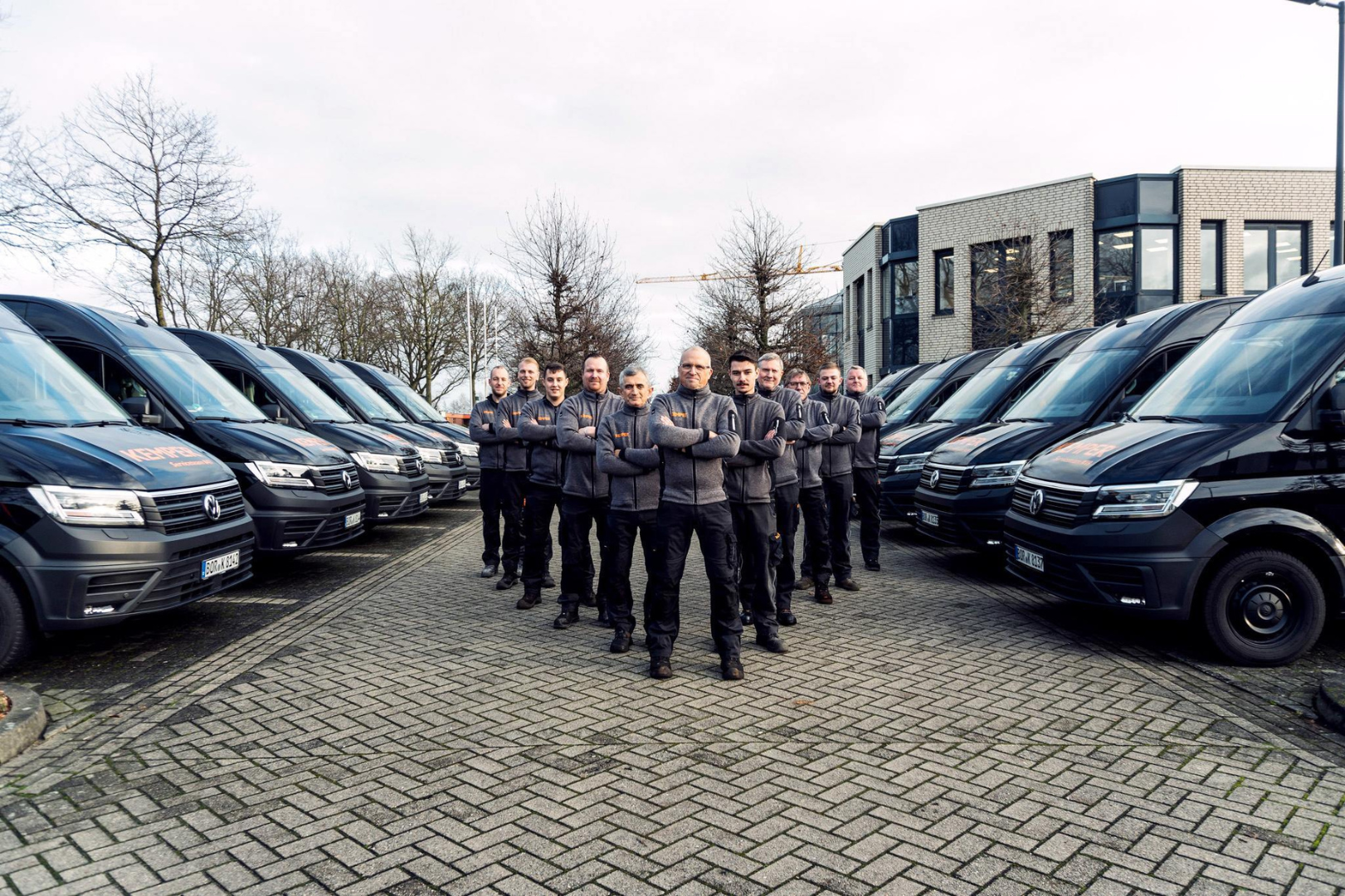 KEMPER Servicetechniker stehen vor ihren Einsatzfahrzeugen und repräsentieren Kompetenz und Einsatzbereitschaft