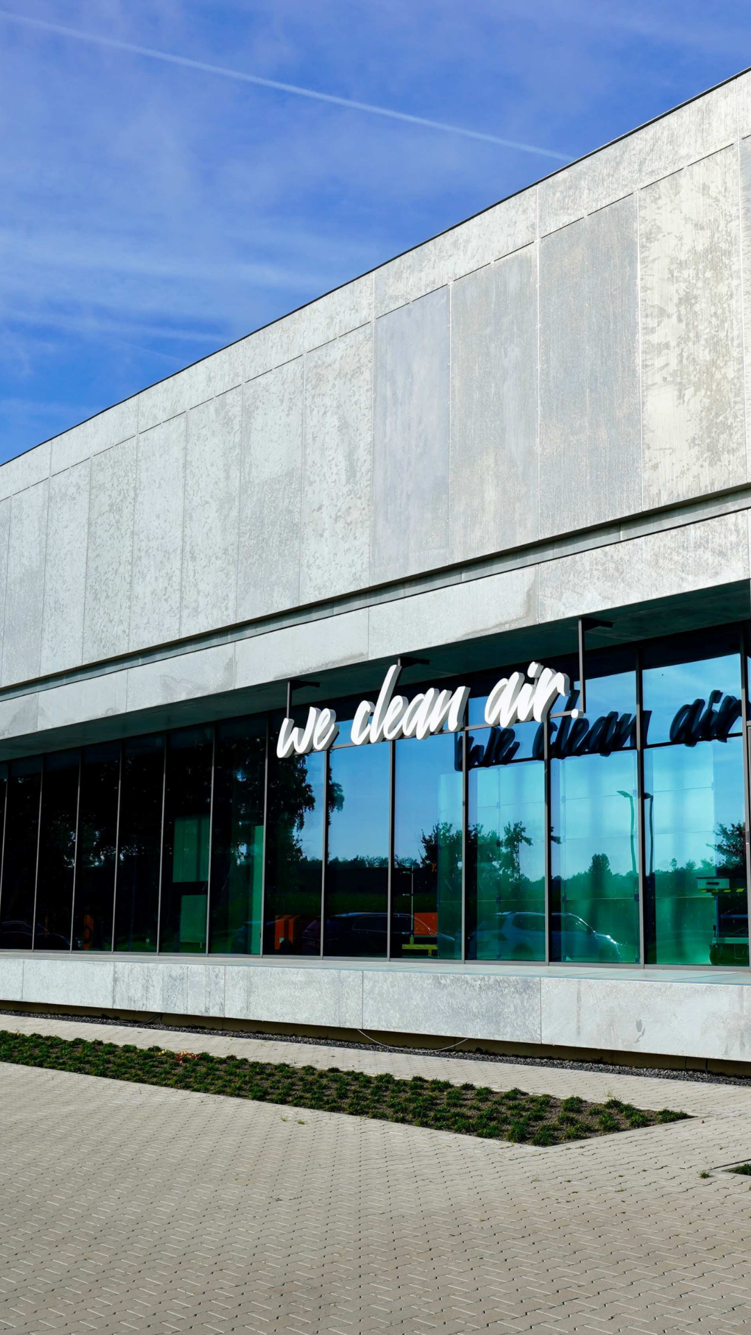 Moderne Gebäudeansicht des KEMPER Headquarters mit Glasfassade und dem Schriftzug „we clean air“