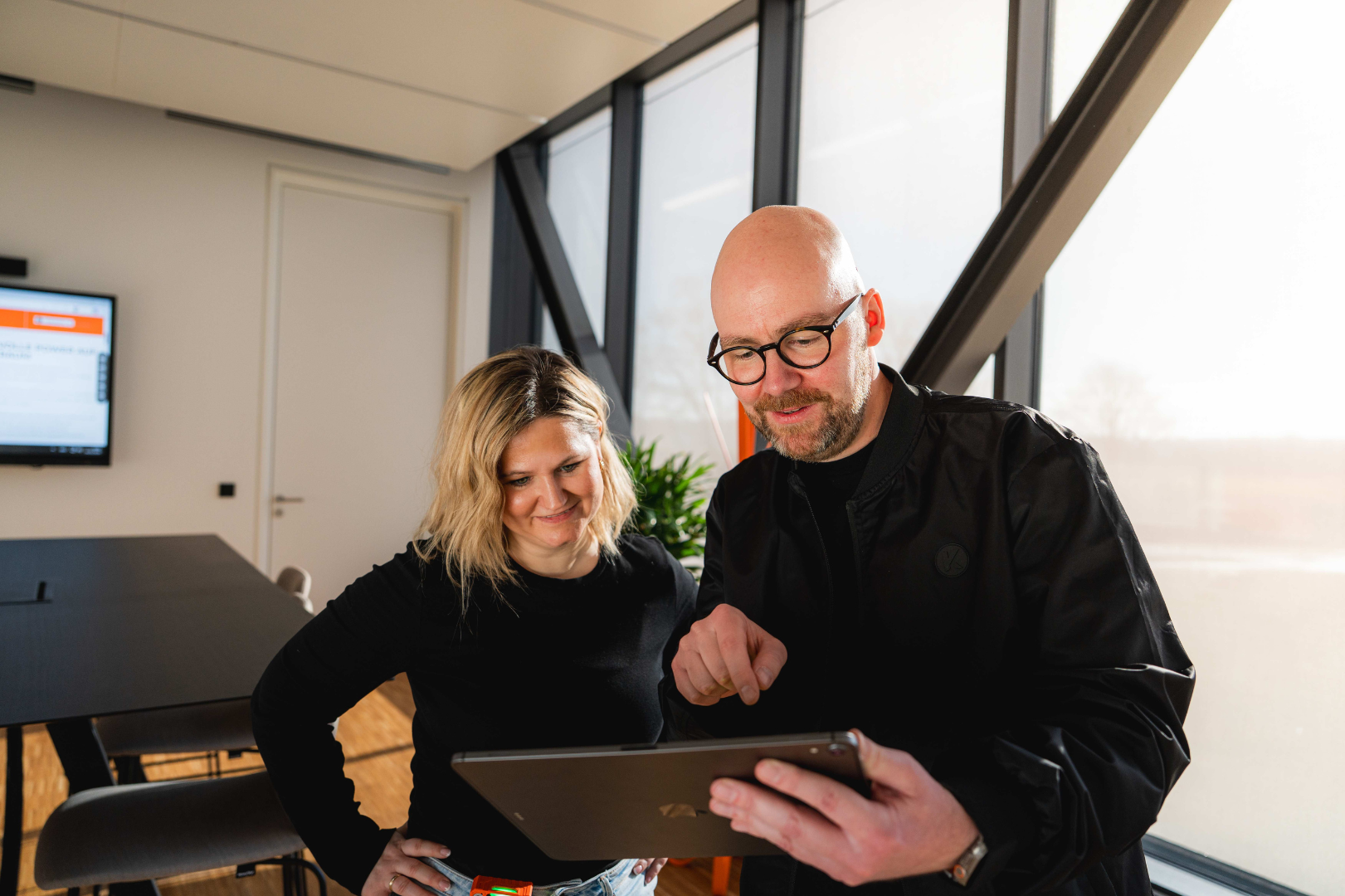 Zwei Mitarbeitende bei KEMPER arbeiten gemeinsam an einem Tablet in modernem Büro