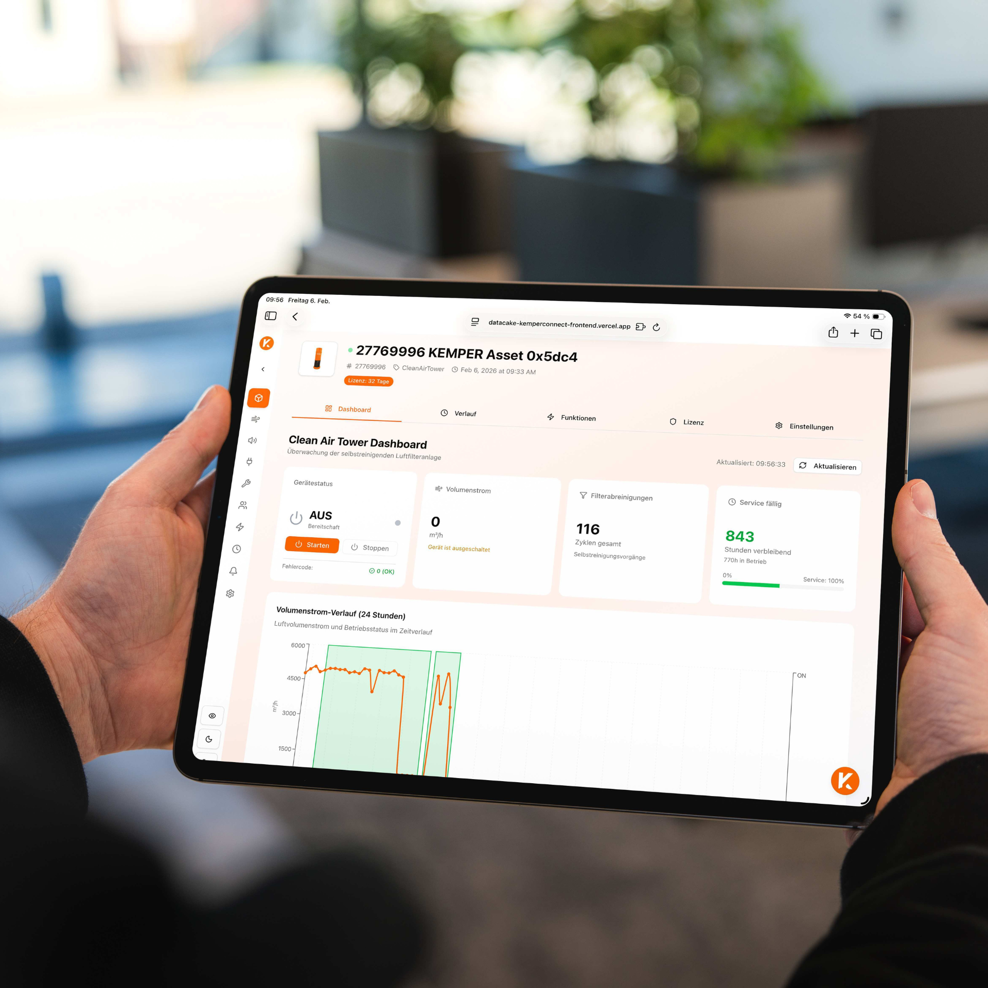 Tablet in Händen mit geöffnetem KEMPER Connect Dashboard zur Überwachung einer Clean Air Tower Luftfilteranlage mit Betriebsdaten und Diagrammen.