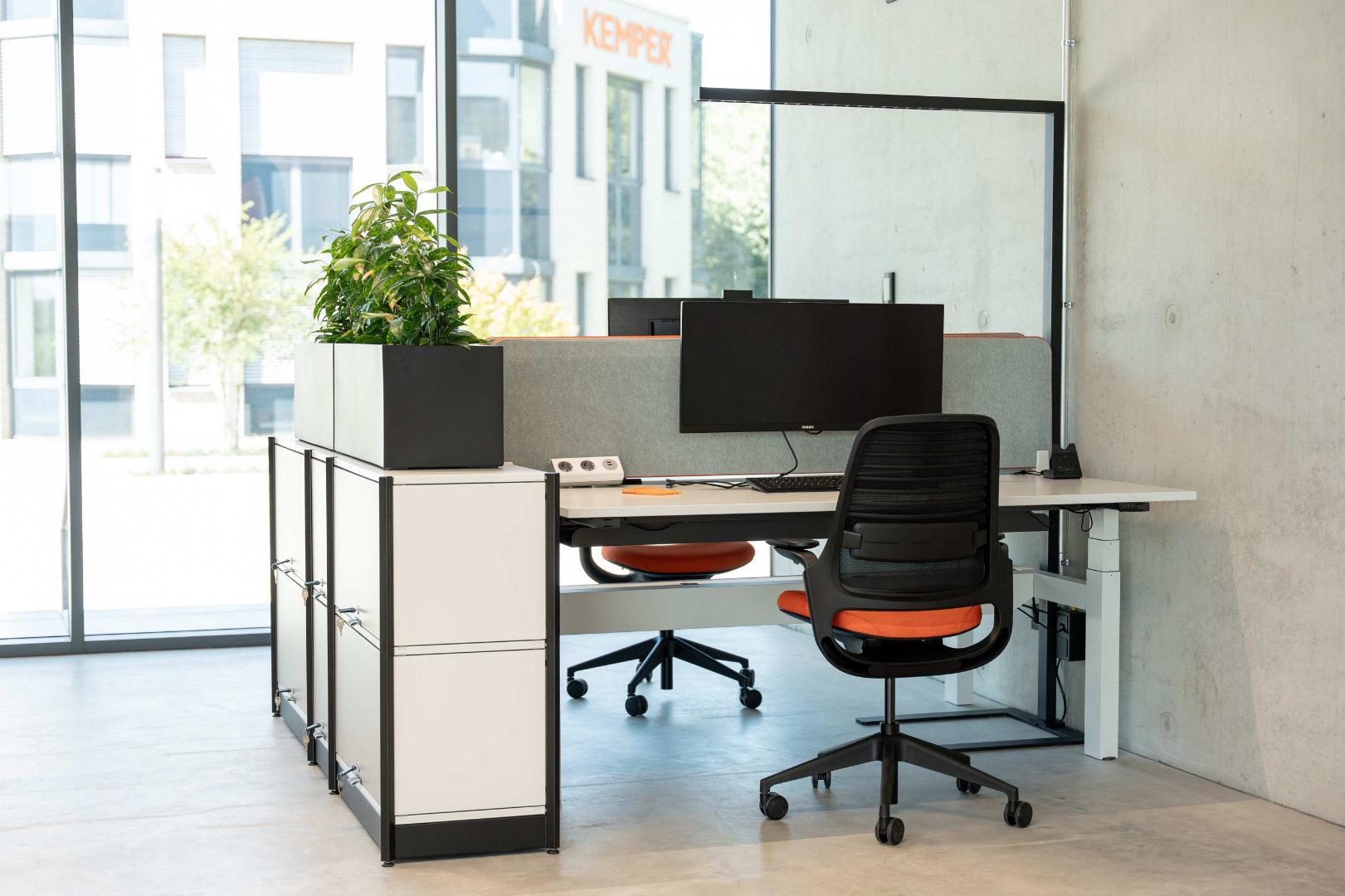 Moderner Büroarbeitsplatz mit Schreibtisch, Monitor, Bürostuhl und Pflanze im KEMPER Headquarter