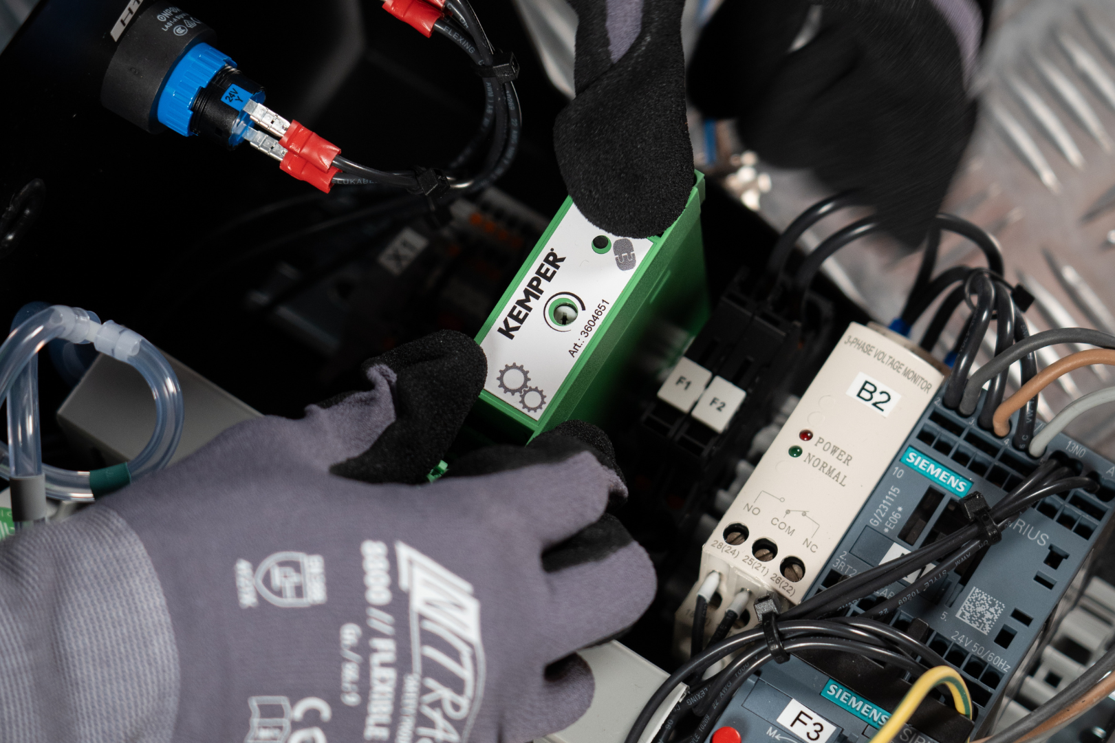 Servicetechniker installiert ein KEMPER Sensormodul in einem Schaltschrank mit elektronischen Komponenten.